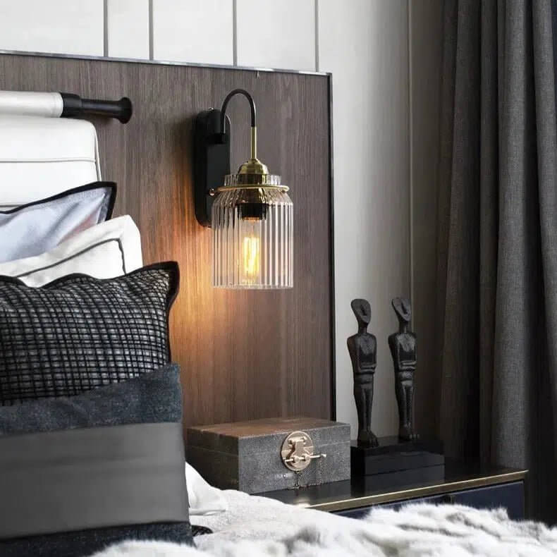 Lima wall light with ribbed glass shade and warm bulb mounted beside a modern bedroom headboard