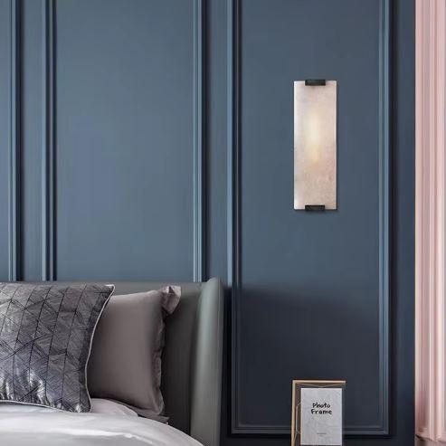 Denver wall light in natural stone and metal mounted on a blue bedroom wall above bedside decor