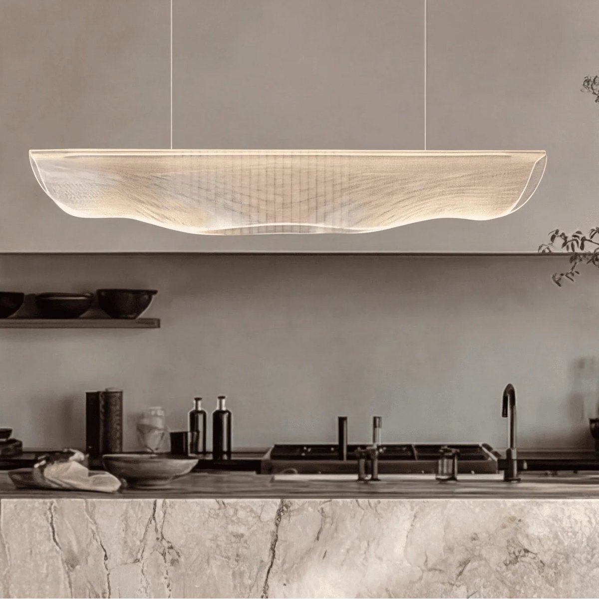 Moroni chandelier modern wave LED pendant light with acrylic shade suspended above a minimalist kitchen island